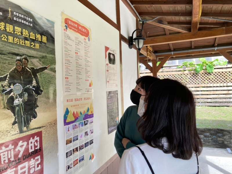 社團法人台灣女性影像學會「2021『因為女性，所以拍片』國片推廣映演計畫」活動紀錄：路人欣賞張貼於布告欄的《我的阿婆是一顆蛋》活動海報（2021/12/04，花蓮鐵道電影院）
